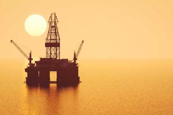 An offshore oil rig with the rising sun behind it