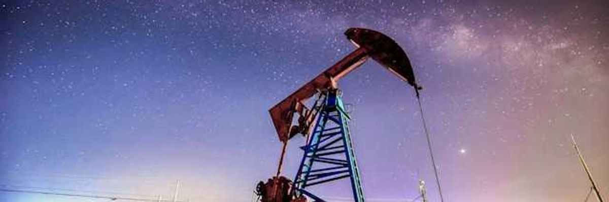 An oil drilling pump jack at night against a starry sky