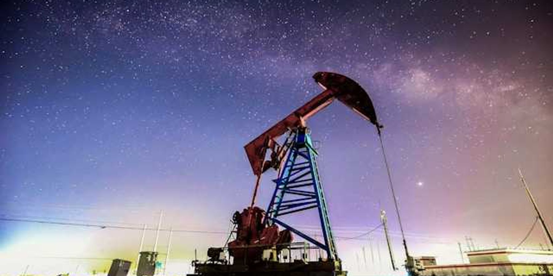 An oil drilling pump jack at night against a starry sky