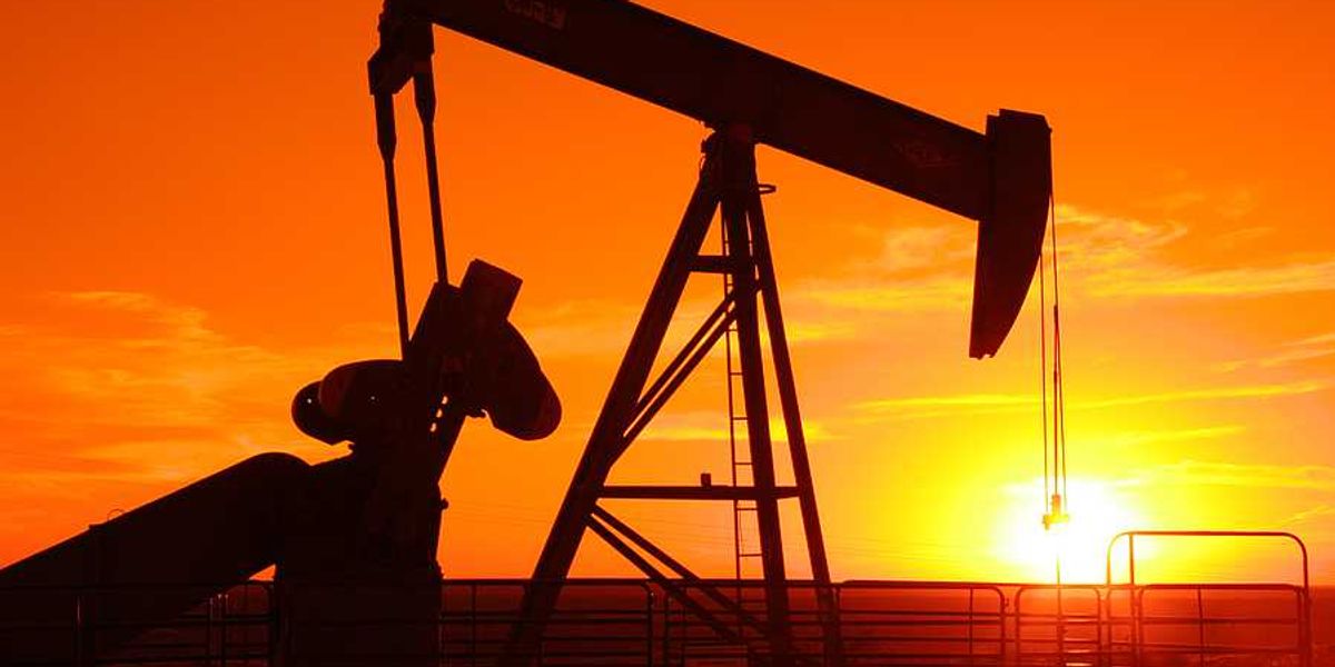 An oil drilling pump jack at sunset