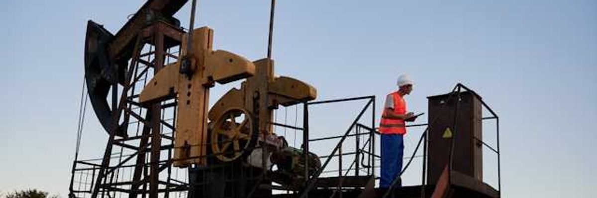 An oil drilling pump jack platform with a worker standing on it