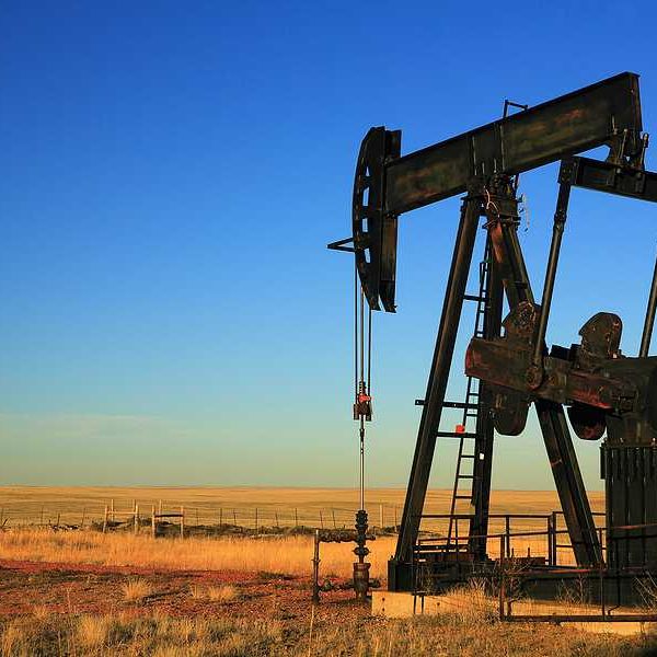 An oil pump jack in the middle of a dry field