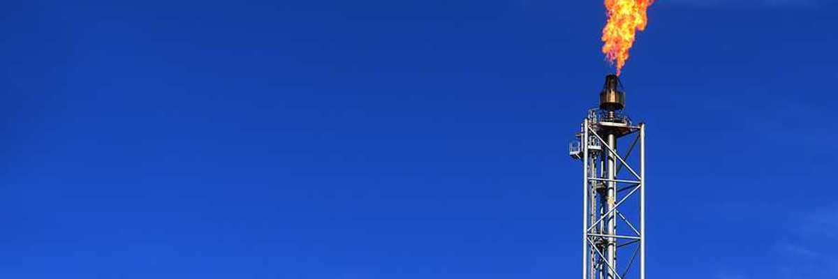 An oil tower with flames during a gas flare against a blue sky