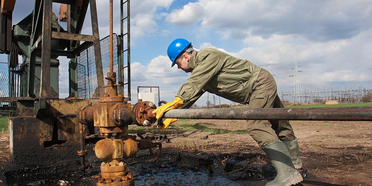 An oil worker using equipment to stop a leak.