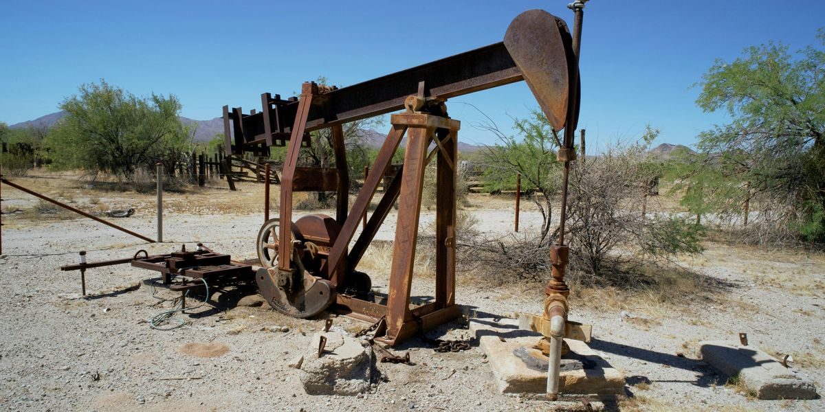An old oil pump sitting in the middle of the desert.