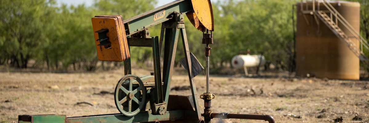 An old oil well pump jack in a field.