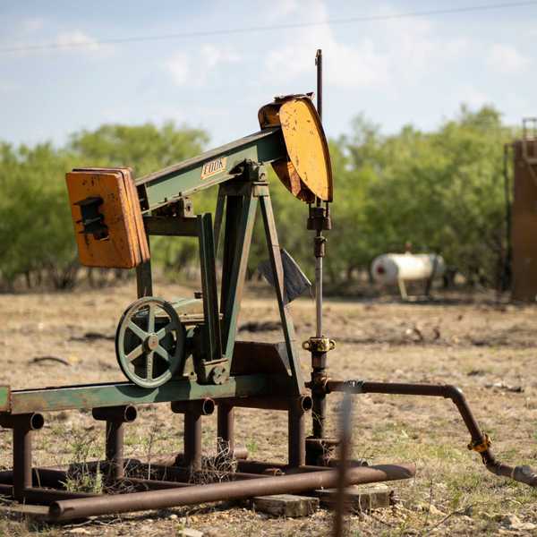 An old oil well pump jack in a field.