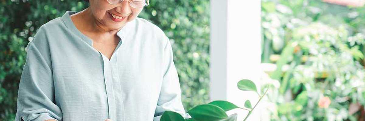 An older Asian woman looking at plants on her patio