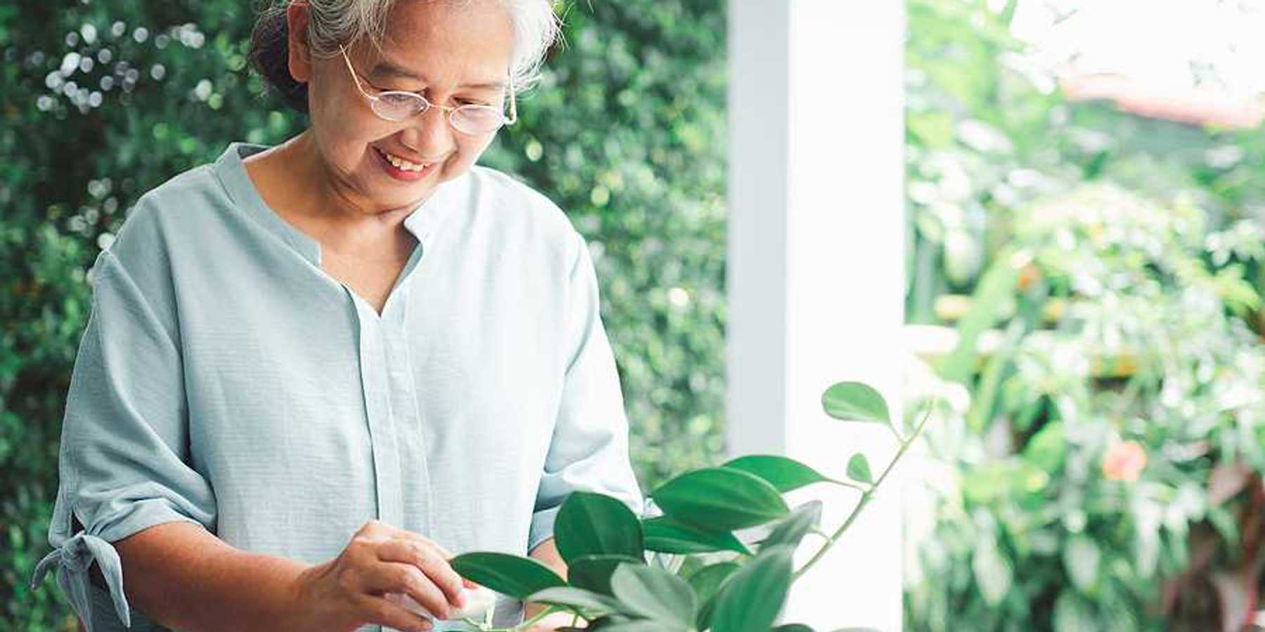 An older Asian woman looking at plants on her patio