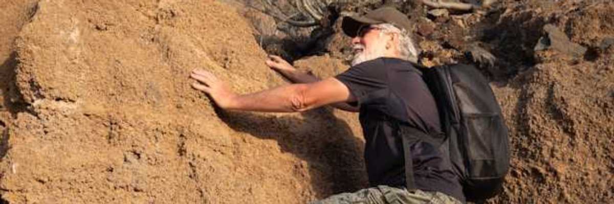 An older man climbing onto a dry rock