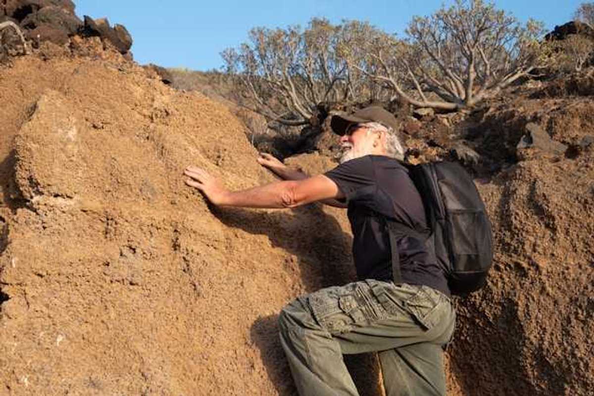An older man climbing onto a dry rock