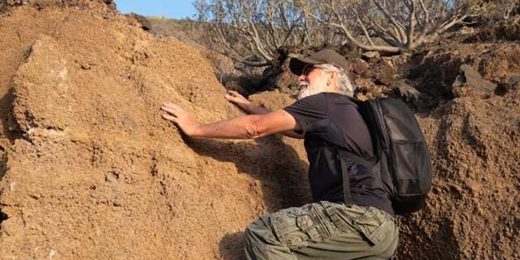 An older man climbing onto a dry rock