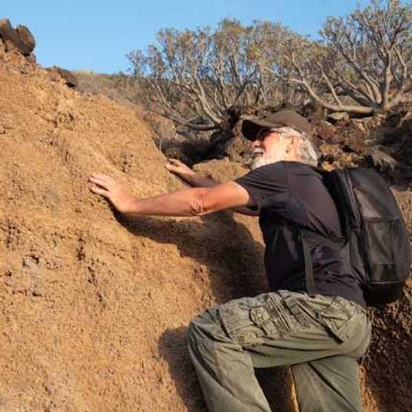An older man climbing onto a dry rock