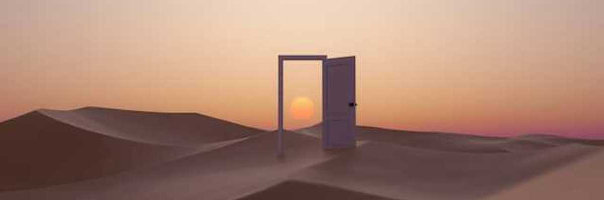An open door in the middle of a desert with a sunset behind
