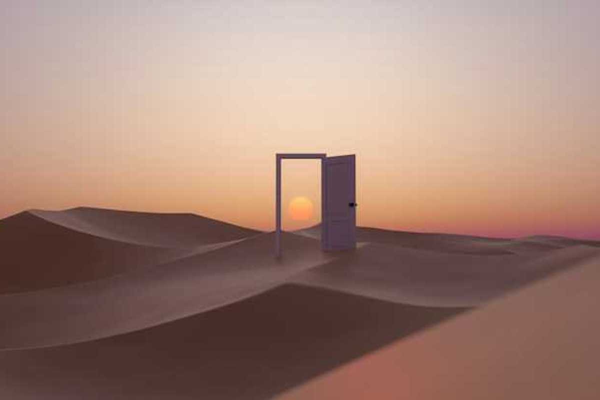 An open door in the middle of a desert with a sunset behind