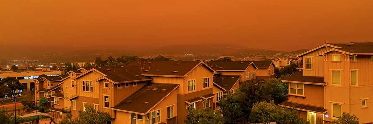 An orange-tinged sky and houses during a wildfire