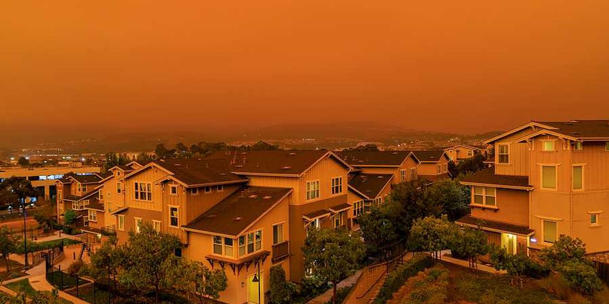 An orange-tinged sky and houses during a wildfire