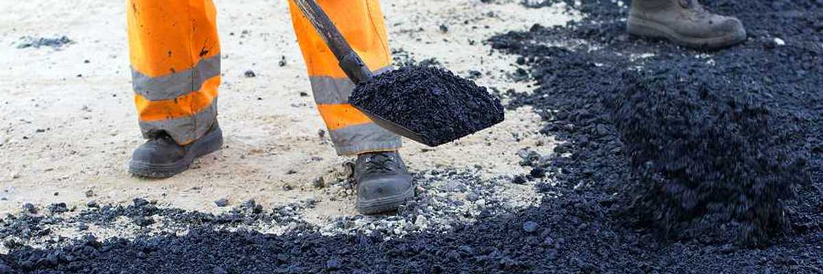An outdoor worker laying asphalt