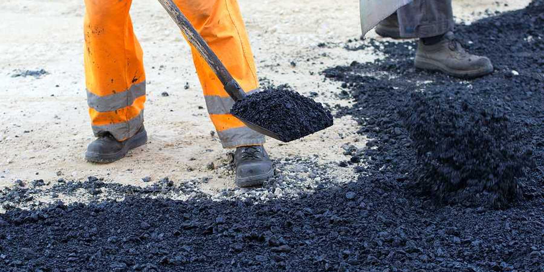 An outdoor worker laying asphalt