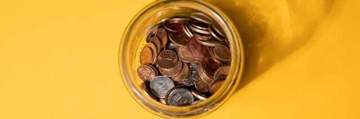 An overhead view of a jar of coins on a yellow background