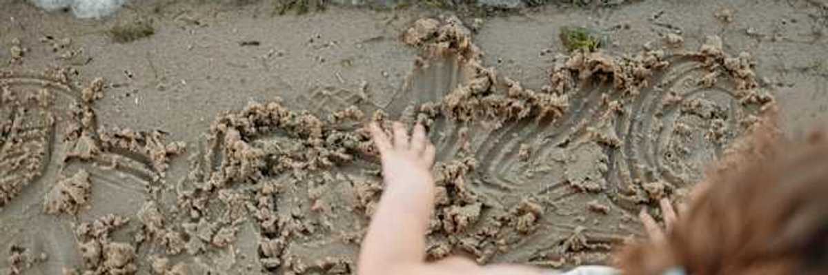 An overhead view of a small child playing in the sand on a beach