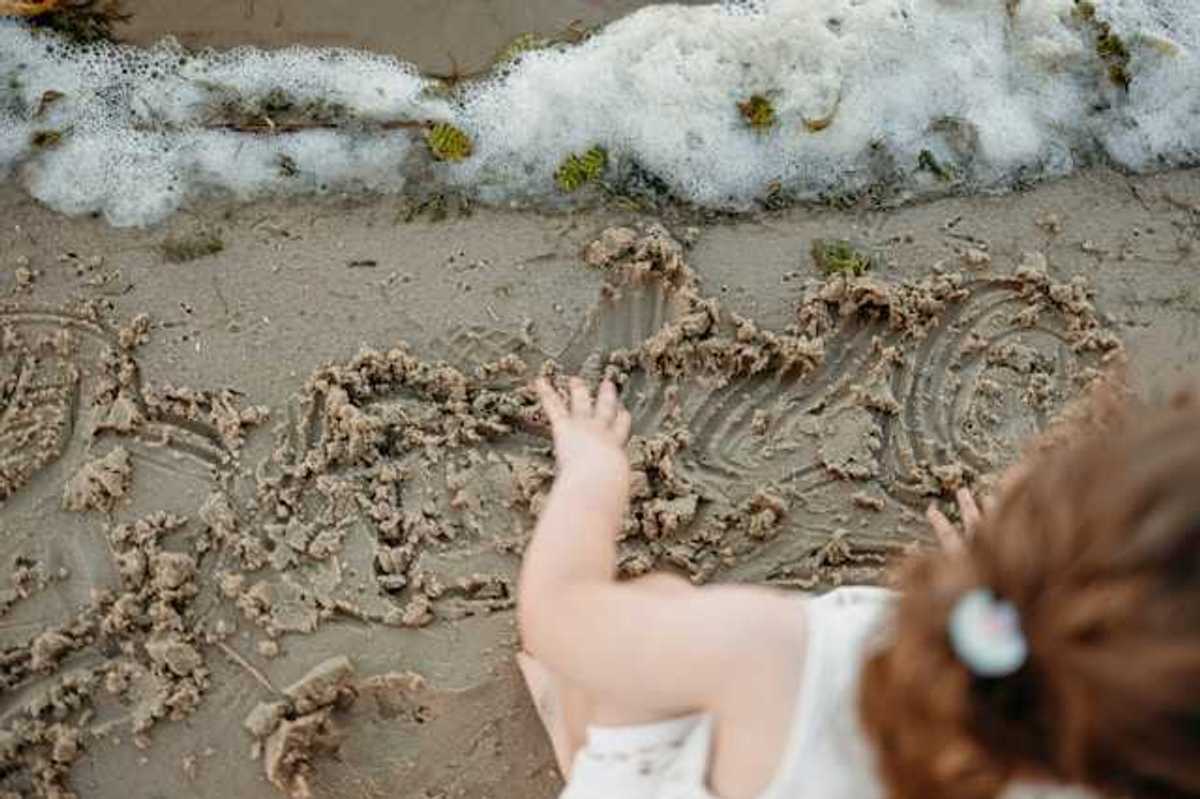 An overhead view of a small child playing in the sand on a beach