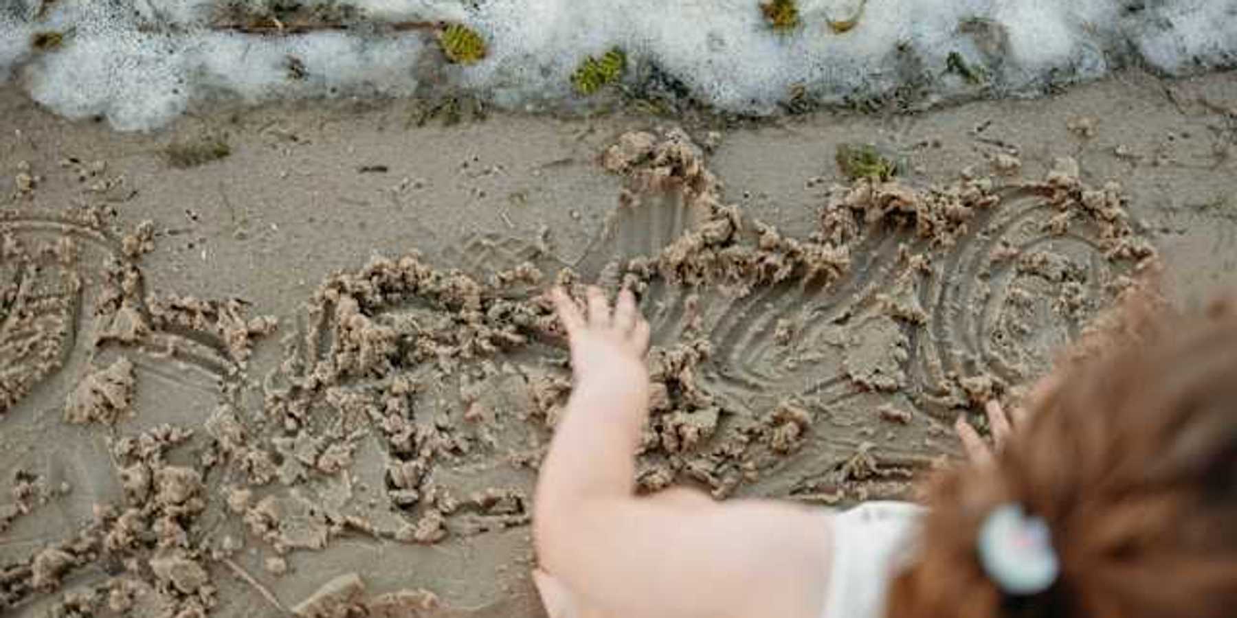 An overhead view of a small child playing in the sand on a beach