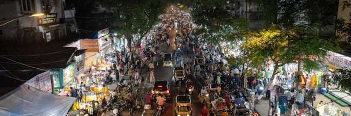 An overhead view of a street in Mumbai, India at night filled with cars, people, and shop entrances