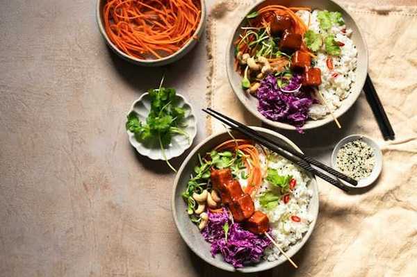 An overhead view of two rice and tofu bowls