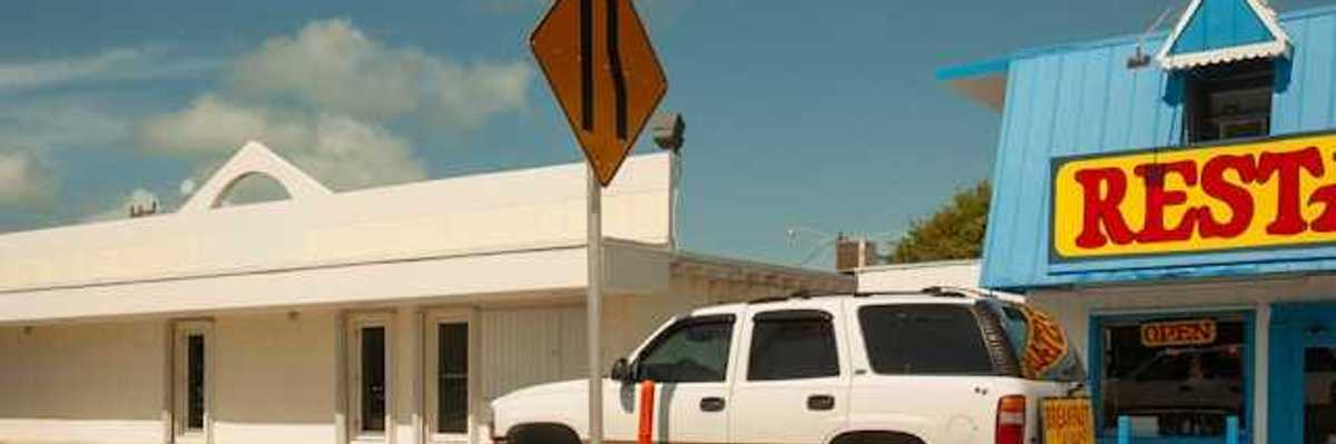 An SUV parked in front of a restaurant on a sunny day
