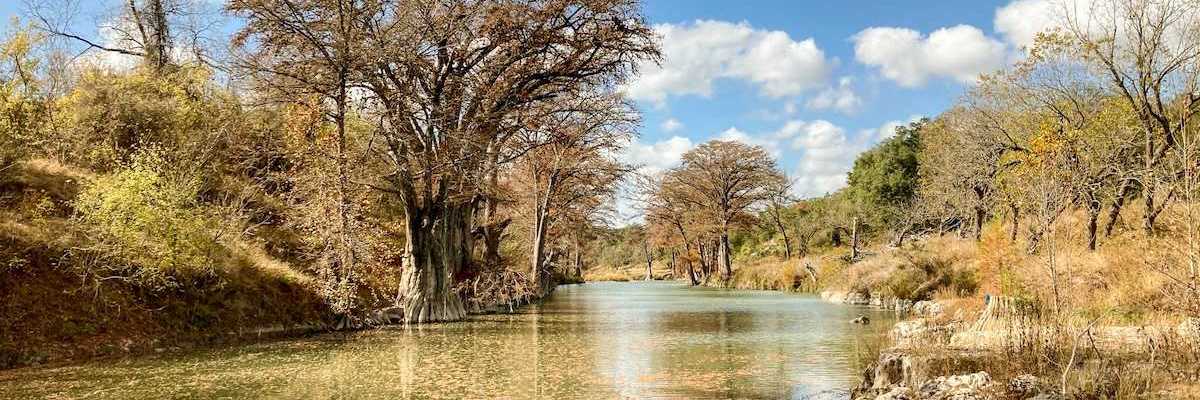 Autumn trees and foliage along the clear water of the Guadalupe River in Texas.