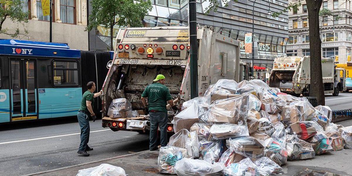 Bags of trash on a New York street being loaded into a dump truck