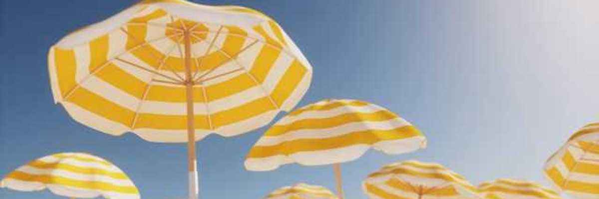 Beach umbrellas with yellow and white stripes against a blue sky
