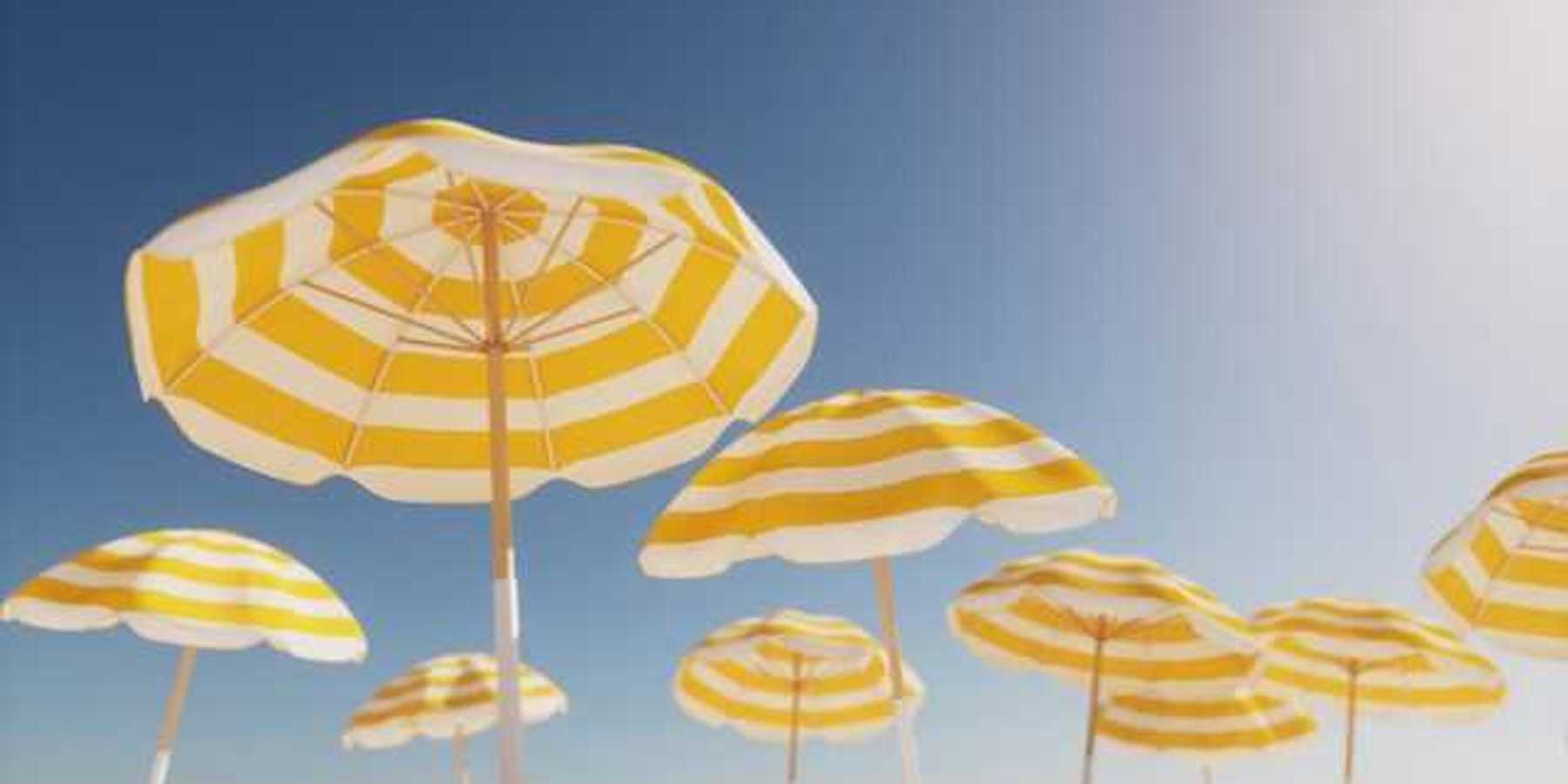 Beach umbrellas with yellow and white stripes against a blue sky
