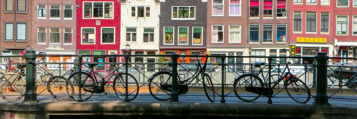 Bicycles leaning against a railing on a bridge over a canal in Amsterdam