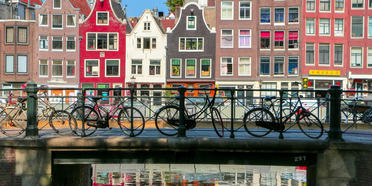 Bicycles leaning against a railing on a bridge over a canal in Amsterdam