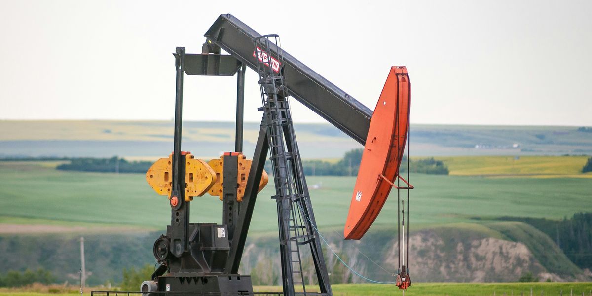 black and orange oil pump jack on green grass field during daytime