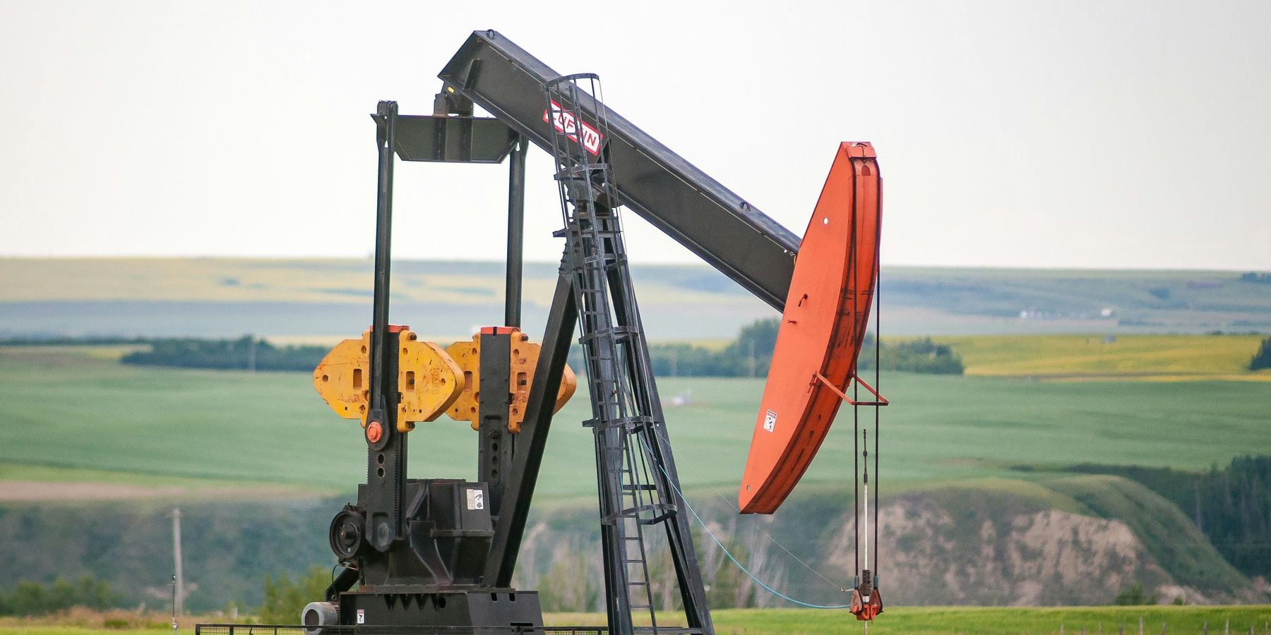 black and orange oil pump jack on green grass field during daytime