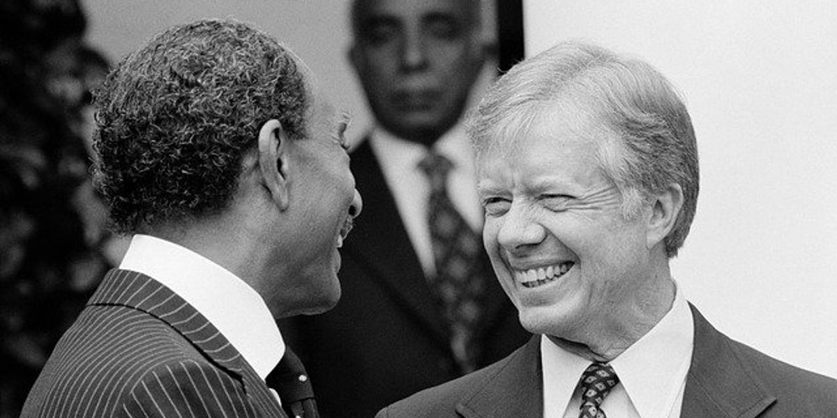 Black and white photo of former president Jimmy Carter smiling at another man