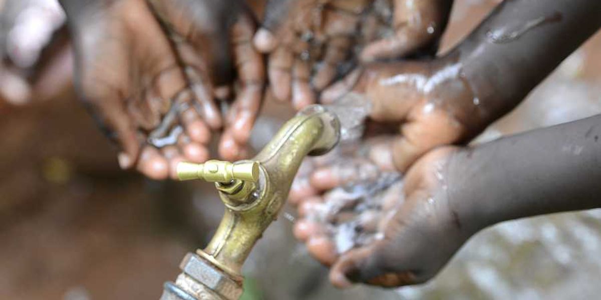 Black children holding their hands under a faucet with water coming out of it
