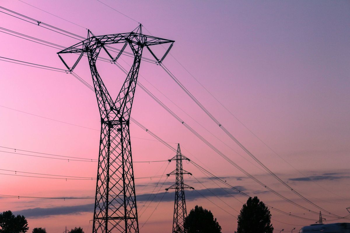 black electricity tower under a pink sky during sunset