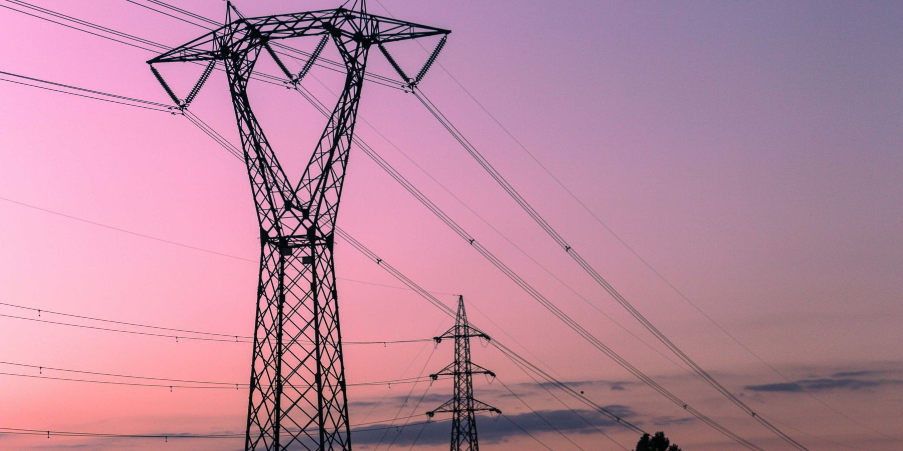 black electricity tower under a pink sky during sunset