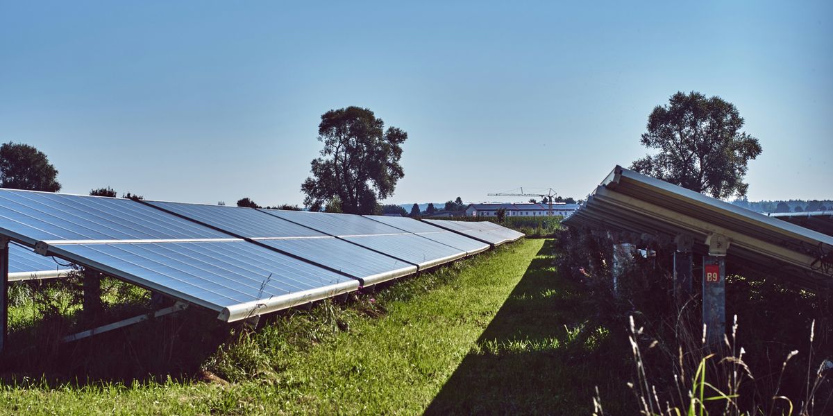 black solar panels on green grass field under blue sky during daytime.
