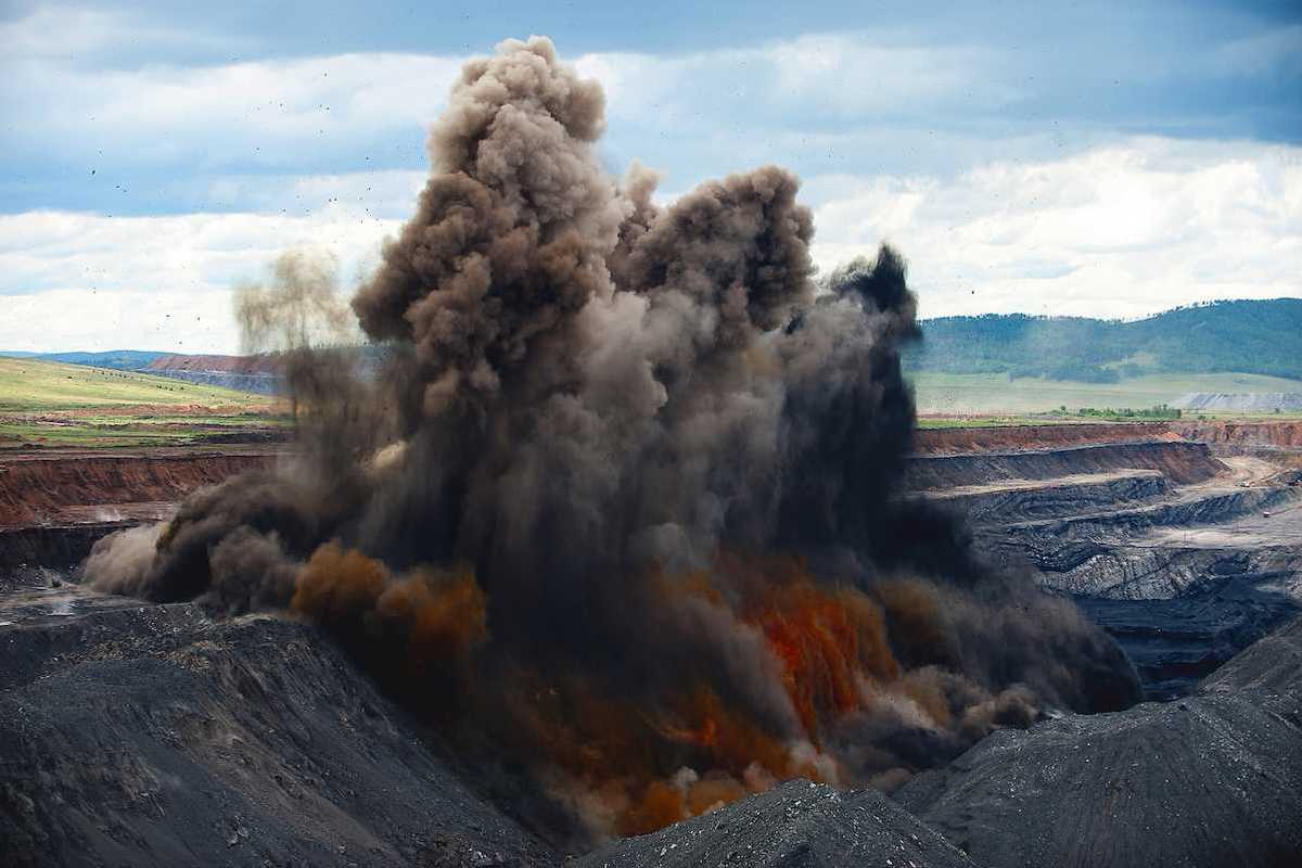 Blasting being carried out at an open pit coal mine. Explosion spewing smoke and debris to remove overburden.
