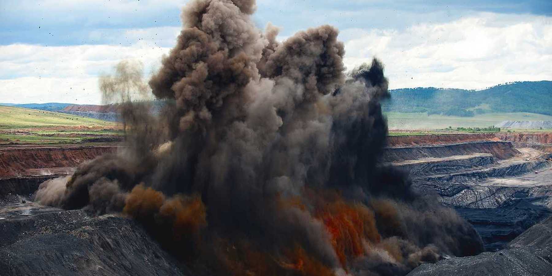 Blasting being carried out at an open pit coal mine. Explosion spewing smoke and debris to remove overburden.
