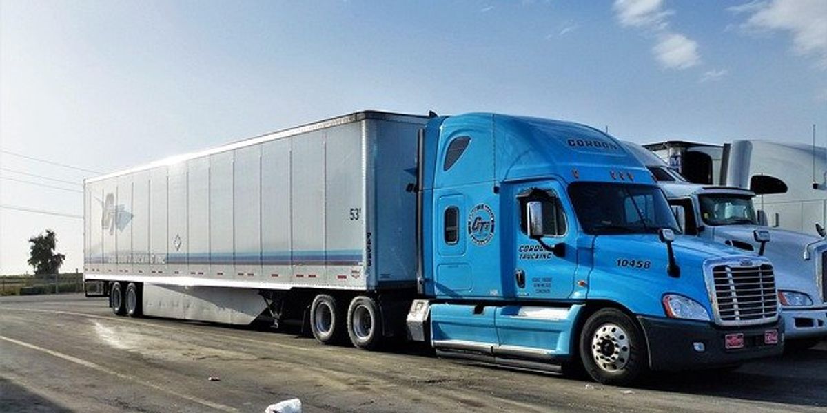 Blue 18-wheeler truck parked on pavement.