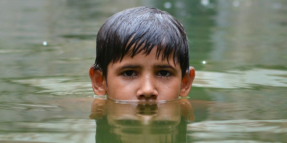 Boy immersed up to nose in floodwaters