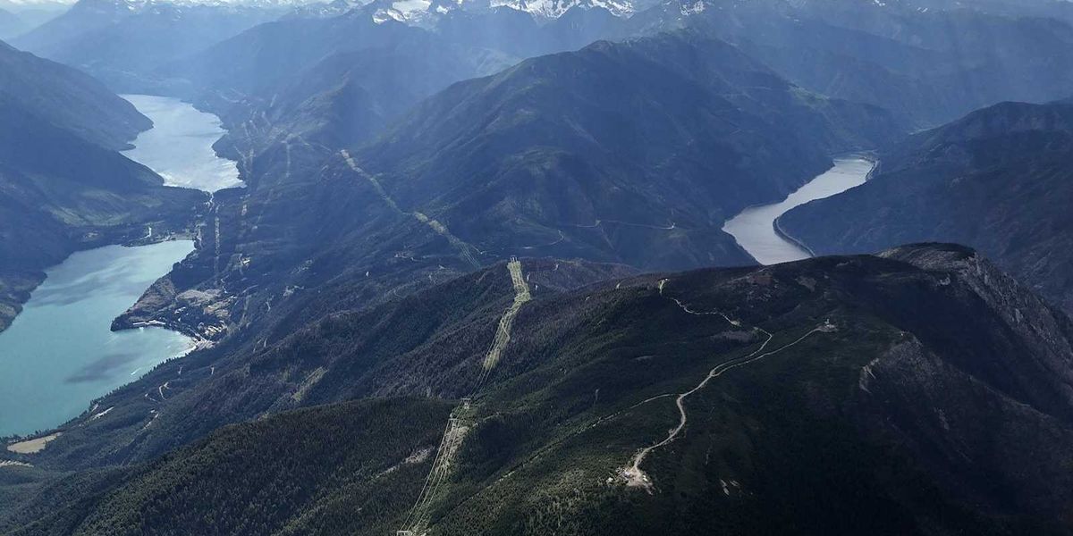 British Columbia landscape with hydro dam, powerlines and snowcapped Canadian Rockies