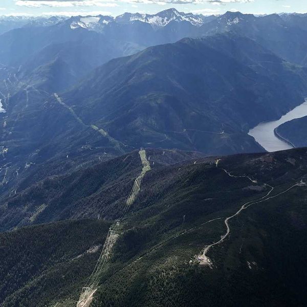 British Columbia landscape with hydro dam, powerlines and snowcapped Canadian Rockies