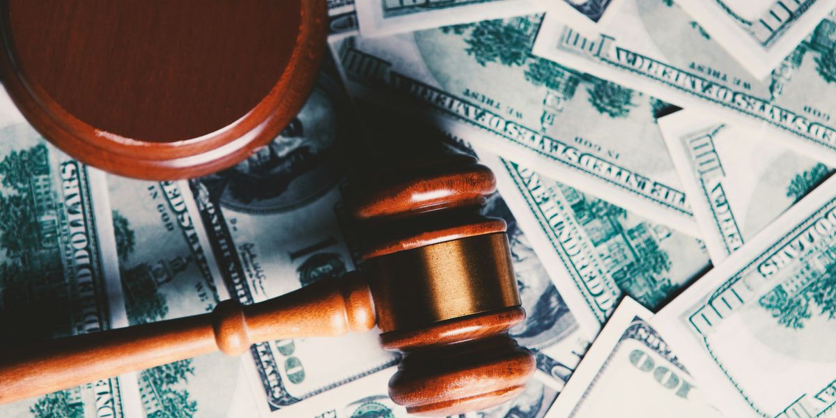 Brown wooden gavel on a bed of $100 dollar bills.